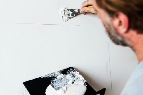 Contractor patching a drywall wall with a putty knife